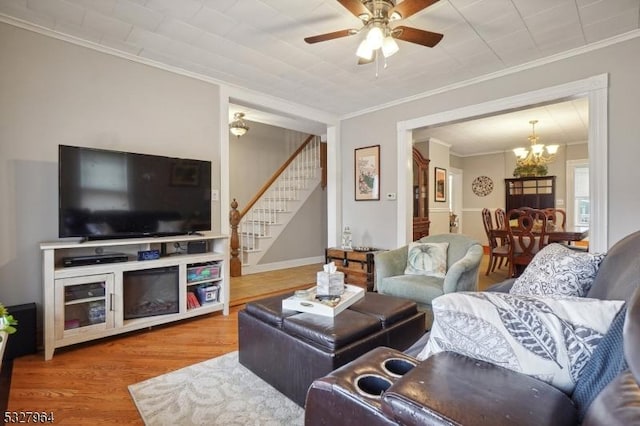 living room with crown molding, wood-type flooring, and ceiling fan with notable chandelier