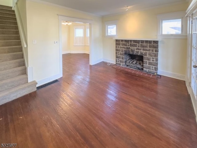 unfurnished living room featuring a fireplace, dark wood-type flooring, a notable chandelier, and ornamental molding