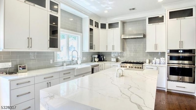 kitchen with light stone countertops, appliances with stainless steel finishes, backsplash, sink, and white cabinetry