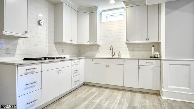 kitchen featuring light hardwood / wood-style floors, white cabinetry, sink, and tasteful backsplash