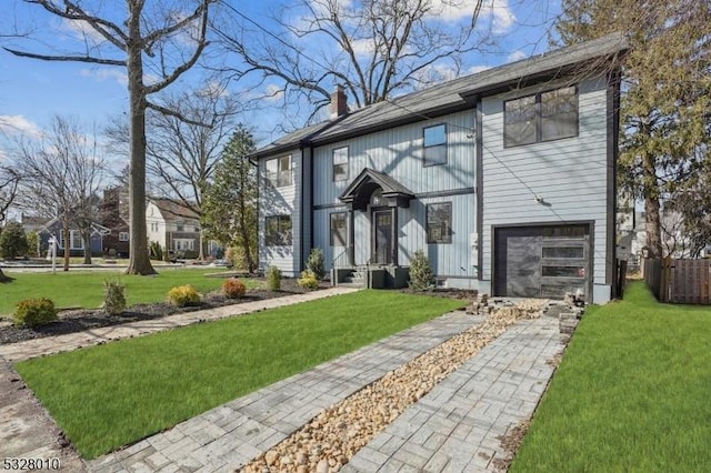 view of front of property featuring a front lawn, a chimney, and an attached garage