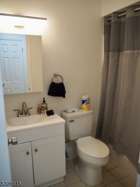 bathroom featuring tile patterned flooring, vanity, toilet, and a shower with shower curtain