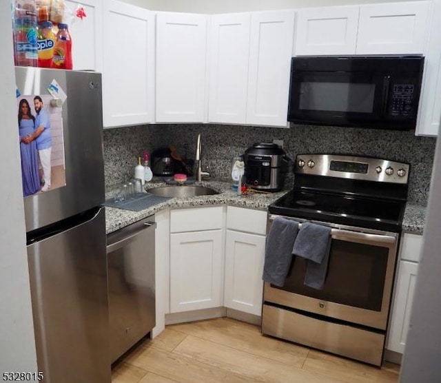 kitchen with sink, light hardwood / wood-style flooring, decorative backsplash, white cabinetry, and stainless steel appliances