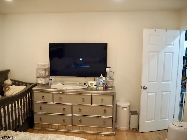 bedroom with a crib and light wood-type flooring