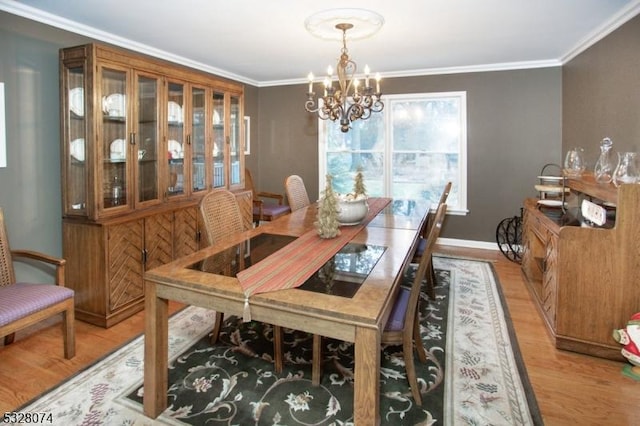 dining area with crown molding, light hardwood / wood-style flooring, and a notable chandelier