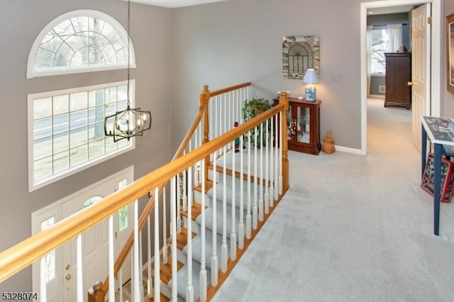 corridor with light carpet and an inviting chandelier