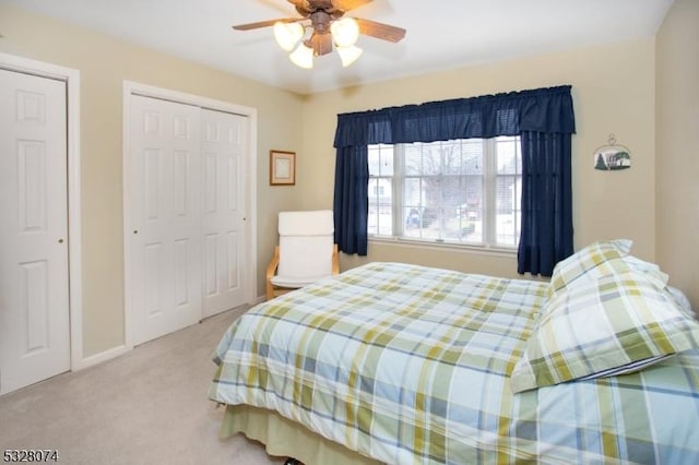 carpeted bedroom with two closets and ceiling fan