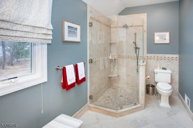 bathroom with tile patterned flooring, a shower with shower door, tile walls, and toilet