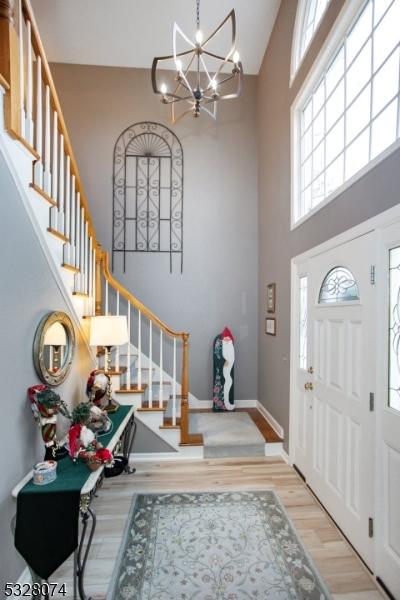 entrance foyer featuring a towering ceiling, light hardwood / wood-style floors, and an inviting chandelier