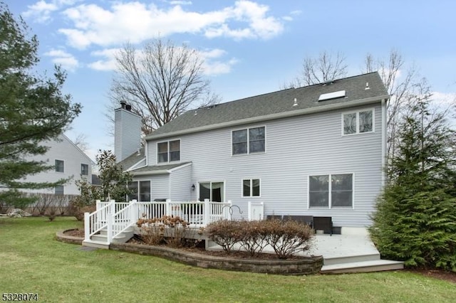 rear view of property featuring a yard and a deck