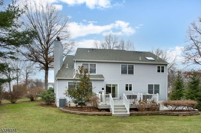 rear view of property with a deck, a yard, and central air condition unit