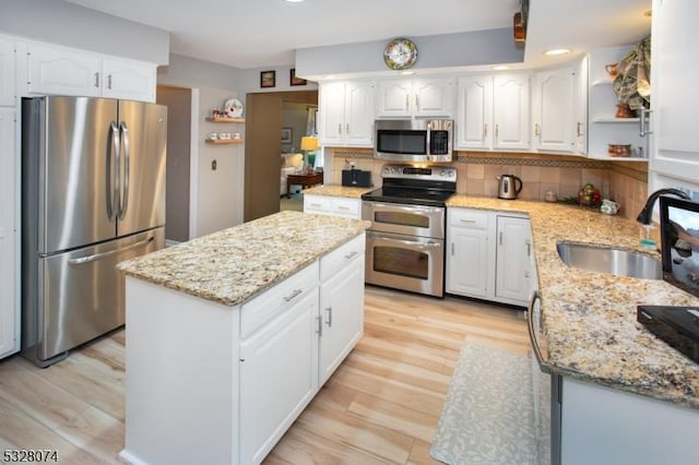 kitchen featuring white cabinets, light stone counters, sink, and appliances with stainless steel finishes