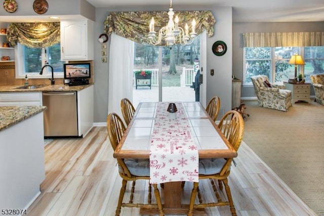 dining room featuring a wealth of natural light, sink, light hardwood / wood-style floors, and an inviting chandelier