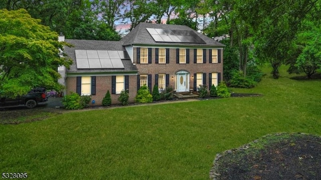 colonial inspired home featuring solar panels and a front lawn