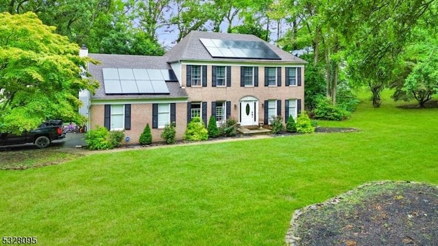 colonial home with a front lawn and solar panels