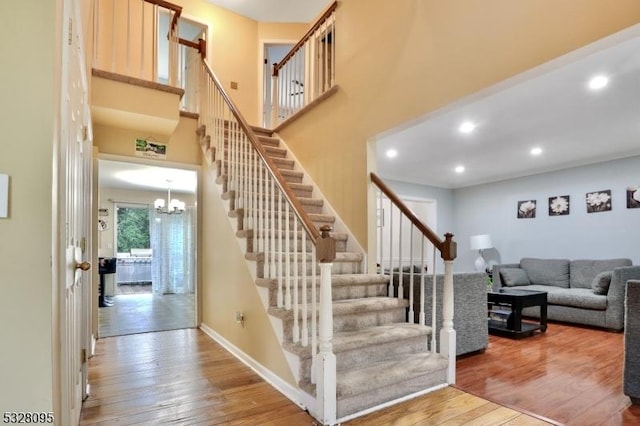 stairs featuring hardwood / wood-style floors and an inviting chandelier