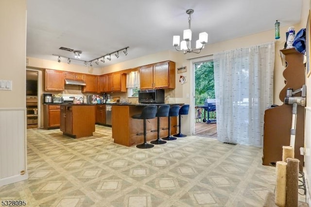 kitchen with an inviting chandelier, stainless steel dishwasher, hanging light fixtures, a kitchen island, and a breakfast bar