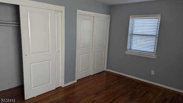 unfurnished bedroom featuring dark hardwood / wood-style flooring and two closets