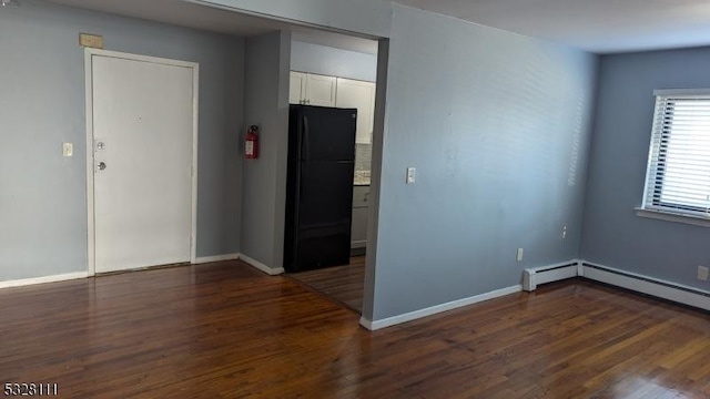 empty room with dark hardwood / wood-style floors and a baseboard heating unit