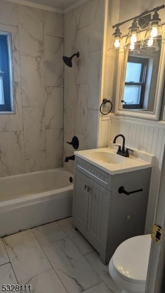 full bathroom with vanity, tiled shower / bath combo, and toilet