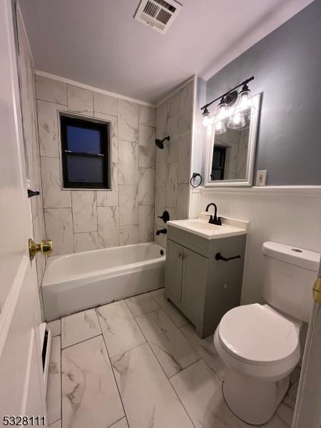 full bathroom with vanity, tiled shower / bath combo, and toilet