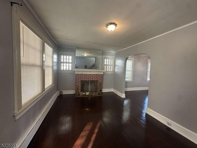 unfurnished living room featuring ornamental molding, dark wood-type flooring, and a brick fireplace