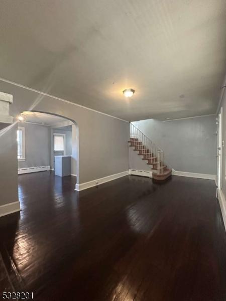 unfurnished living room with dark hardwood / wood-style floors and a baseboard heating unit