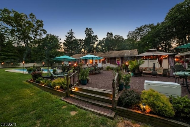 back house at dusk with a gazebo and a yard