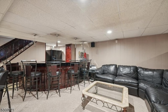 living room with indoor bar, light colored carpet, and a drop ceiling