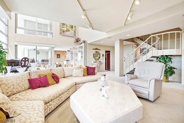 carpeted living room featuring rail lighting and a high ceiling