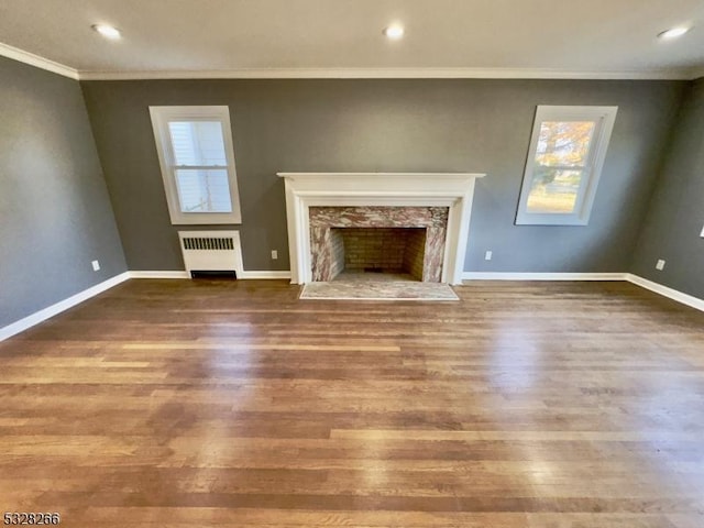 unfurnished living room with radiator, crown molding, a high end fireplace, and wood-type flooring