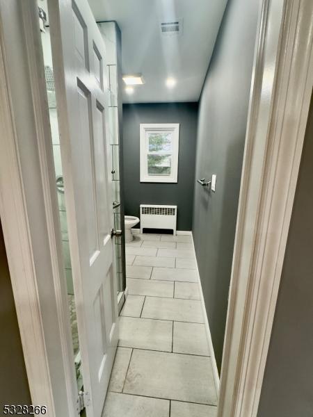 bathroom featuring tile patterned floors, toilet, and radiator