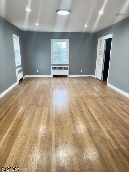 empty room featuring radiator and light hardwood / wood-style floors