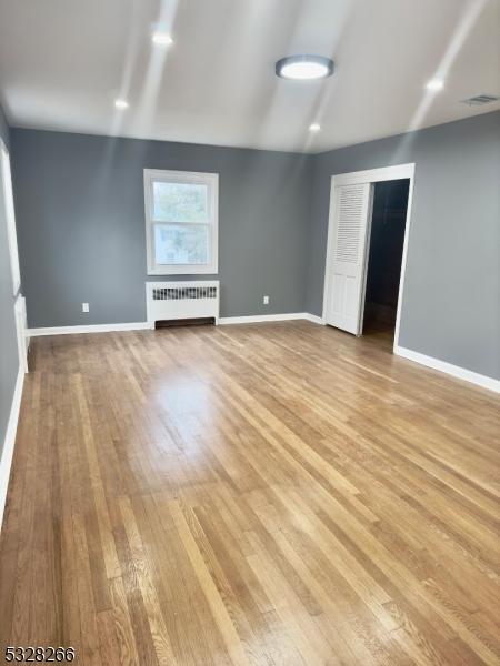 unfurnished living room featuring light wood-type flooring and radiator