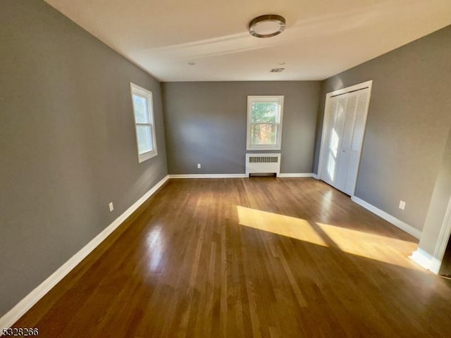 unfurnished room featuring hardwood / wood-style floors and radiator