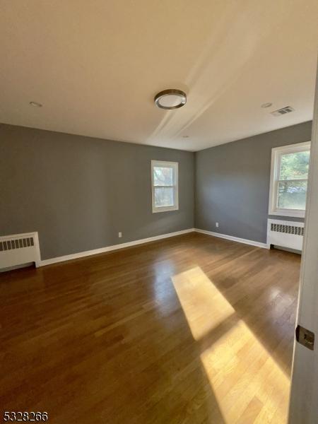 spare room with dark hardwood / wood-style floors and radiator heating unit