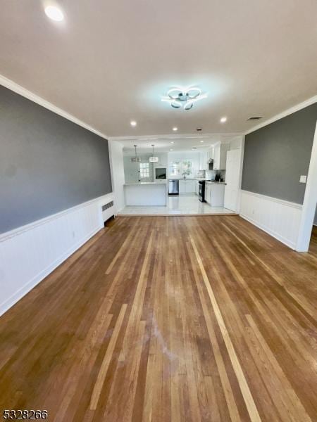 unfurnished living room featuring wood-type flooring and crown molding