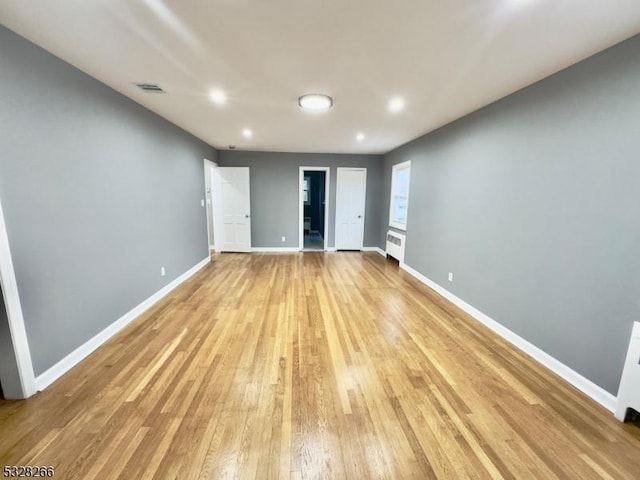 spare room featuring radiator heating unit and light wood-type flooring