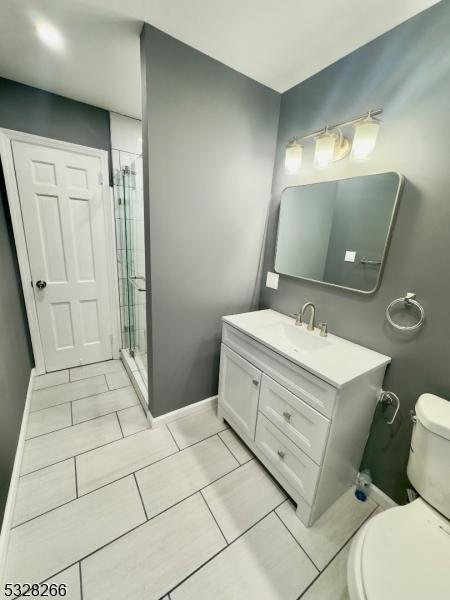 bathroom featuring tile patterned floors, vanity, toilet, and a shower with shower door