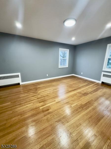 spare room featuring radiator and hardwood / wood-style floors