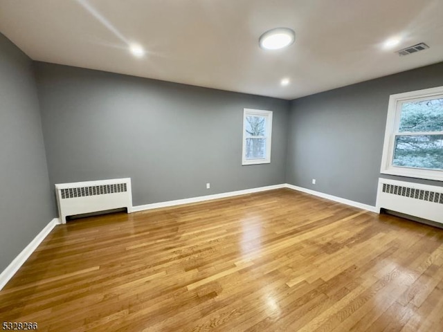 unfurnished room with plenty of natural light, light wood-type flooring, and radiator