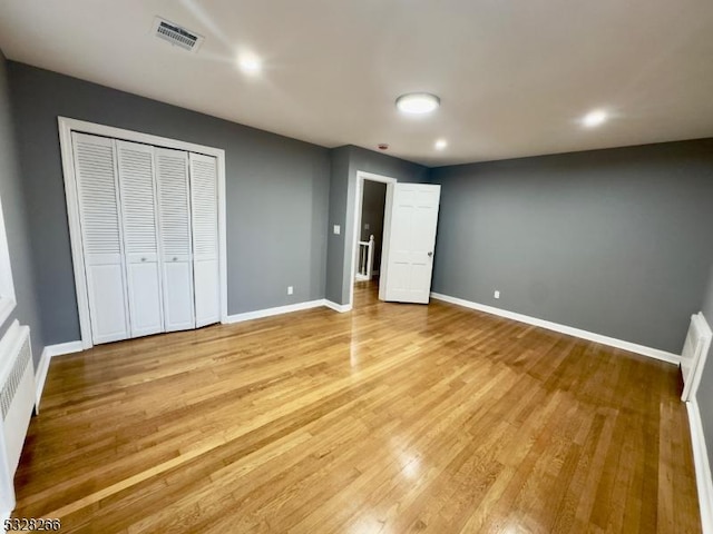 unfurnished bedroom featuring light hardwood / wood-style flooring and radiator