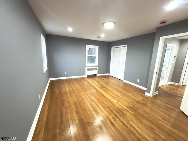 unfurnished bedroom featuring radiator heating unit and hardwood / wood-style flooring