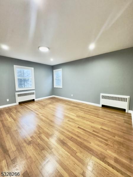 unfurnished room featuring radiator and light hardwood / wood-style flooring