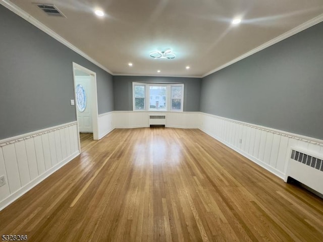 unfurnished room with light hardwood / wood-style floors, radiator, and crown molding