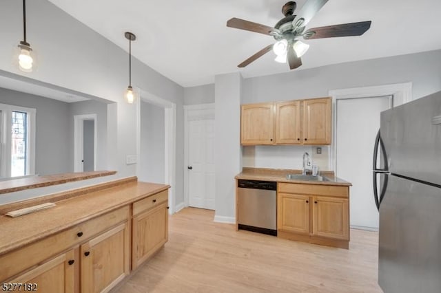 kitchen featuring light brown cabinetry, stainless steel appliances, sink, light hardwood / wood-style floors, and hanging light fixtures