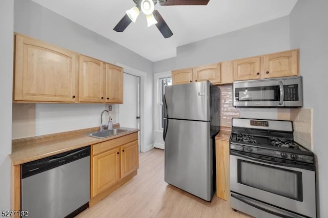 kitchen with appliances with stainless steel finishes, light wood-type flooring, light brown cabinetry, and sink