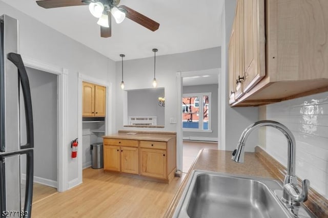 kitchen featuring hanging light fixtures, sink, stainless steel fridge, light brown cabinetry, and light hardwood / wood-style floors