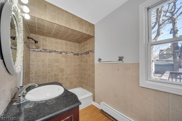 bathroom featuring hardwood / wood-style floors, vanity, tile walls, and a baseboard heating unit