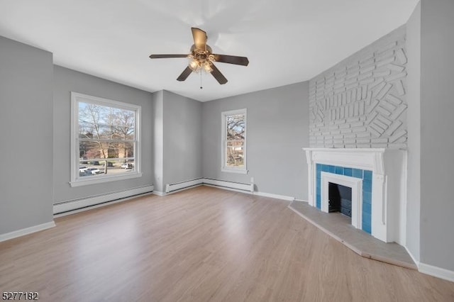 unfurnished living room with ceiling fan, a fireplace, a baseboard radiator, and light hardwood / wood-style flooring